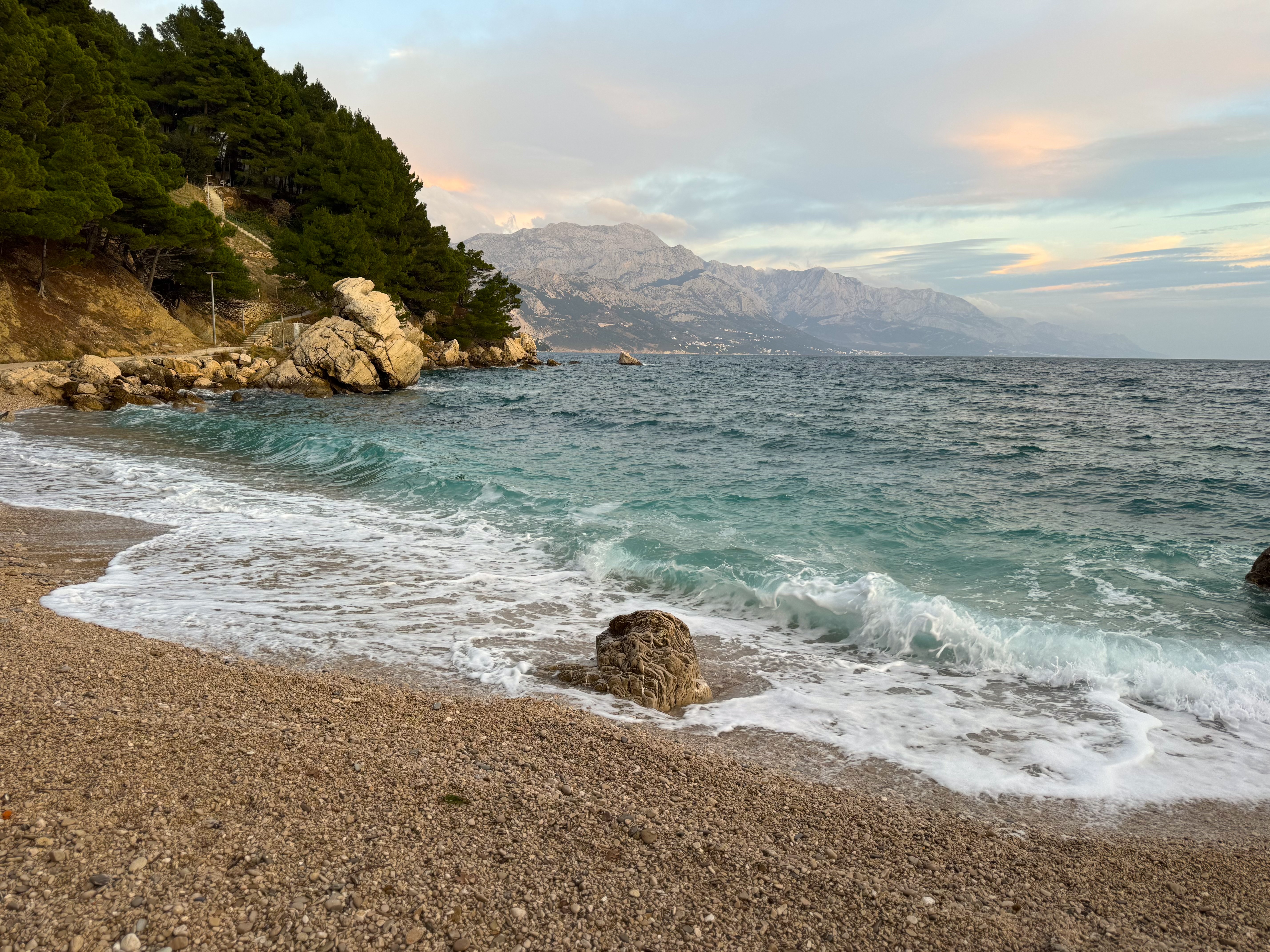 Valovi na plaži uz stijene i borove